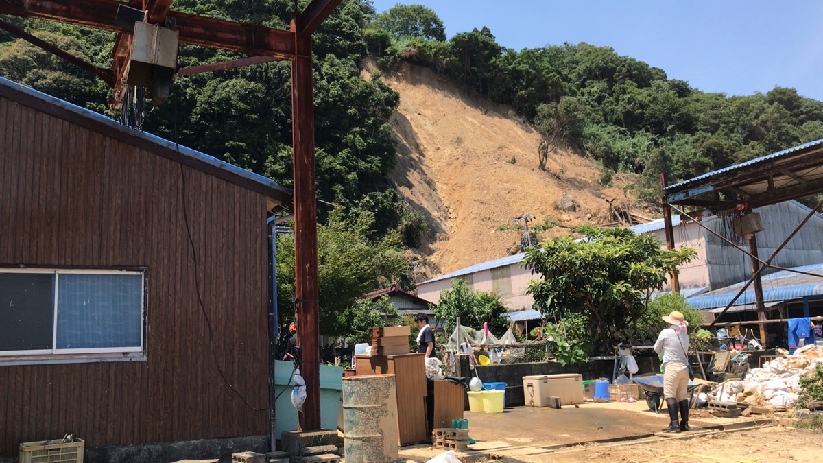 豪雨で山肌が大きく崩れ、住宅のすぐ裏まで土砂が迫っている様子